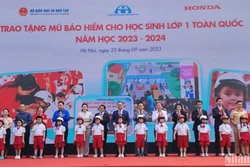 Đại diện Ban tổ chức trao tặng mũ bảo hiểm cho các em học sinh Trường tiểu học Phú Đô (Hà Nội). Ảnh: nhandan.vn