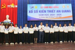 Ông Nguyễn Tấn Danh, Chủ tịch Hội Khuyến học tỉnh An Giang và bà Phan Thị Minh Hiếu, Phó Giám đốc Công ty Trách nhiệm hữu hạn Một thành viên Xổ số kiến thiết tỉnh An Giang trao học bổng cho các em học sinh, sinh viên nghèo hiếu học. Ảnh: Công Mạo - TTXVN